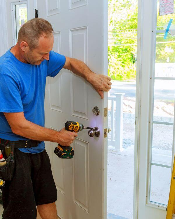 man with a drill finishing the door knob on a new door